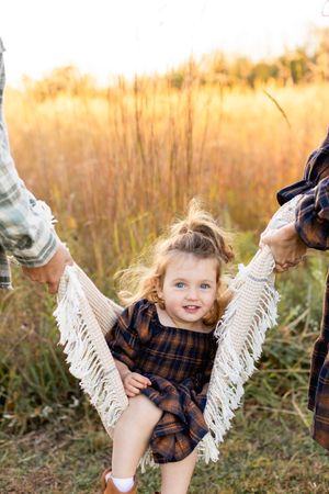 A series of playful poses in a grassy field at golden hour with a white fringe blanket.