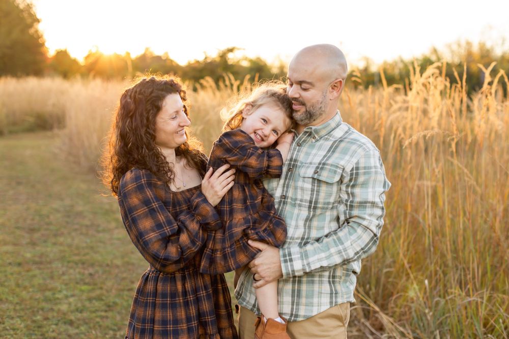 Couple embraces lovingly in a golden wheat field at sunset during an outdoor photoshoot. Nj Family Photographer in Sussex County
