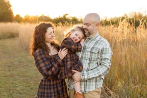 Couple embraces lovingly in a golden wheat field at sunset during an outdoor photoshoot. Nj Family Photographer in Sussex County