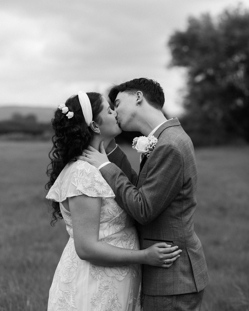 A couple dances playfully on a grassy lawn, spinning and laughing together in a joyful moment.