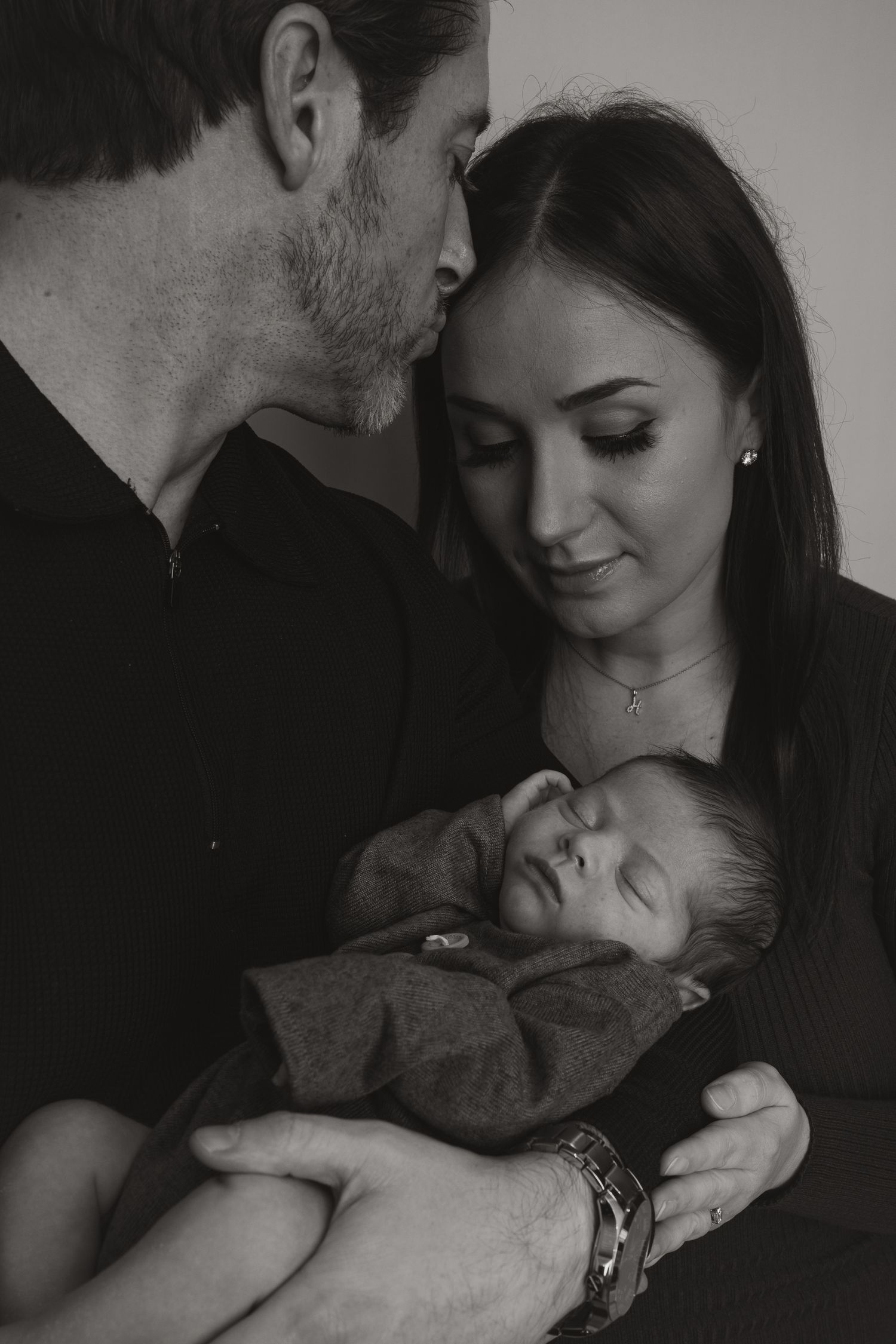 Newborn Photography - A tender moment between parent and baby in white against a light background, shown in three sequential poses.