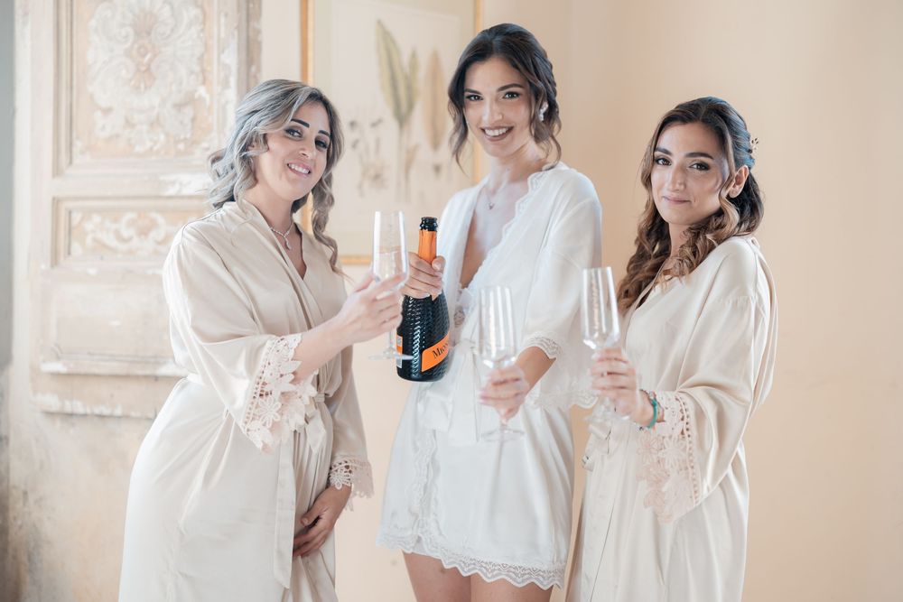 A group in white robes enjoying drinks and celebrating together in an elegant, light-filled room.