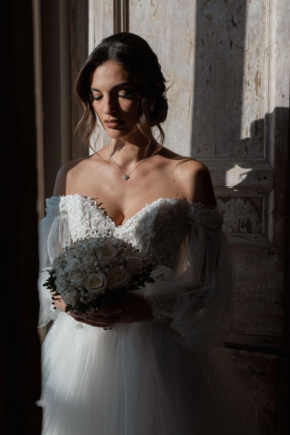 Dramatic bridal portraits showing a white wedding gown with delicate lace details in moody indoor lighting.