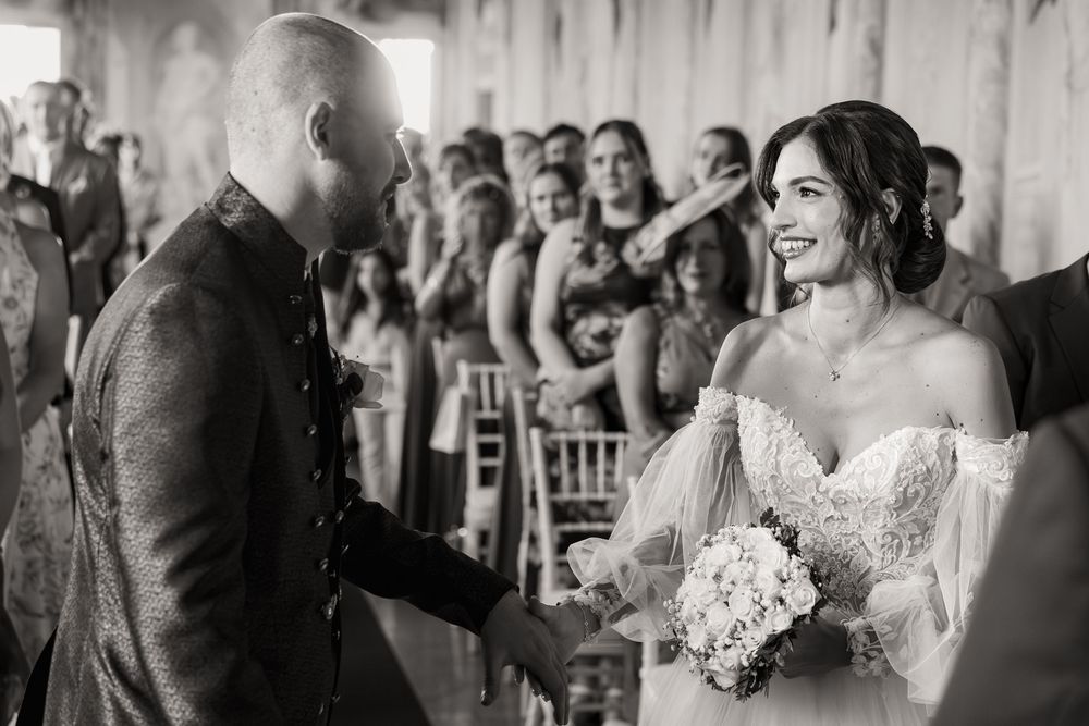 Black and white wedding ceremony photo capturing an emotional moment in an elegant venue.