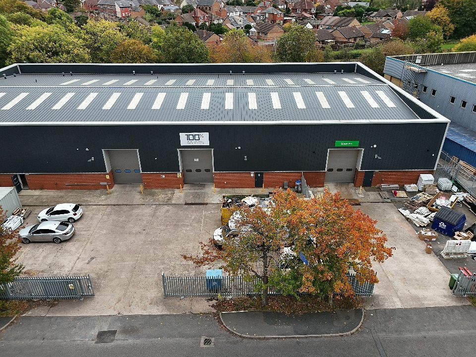 Aerial view of commercial warehouse buildings with white roofs and parking lots in an industrial area.