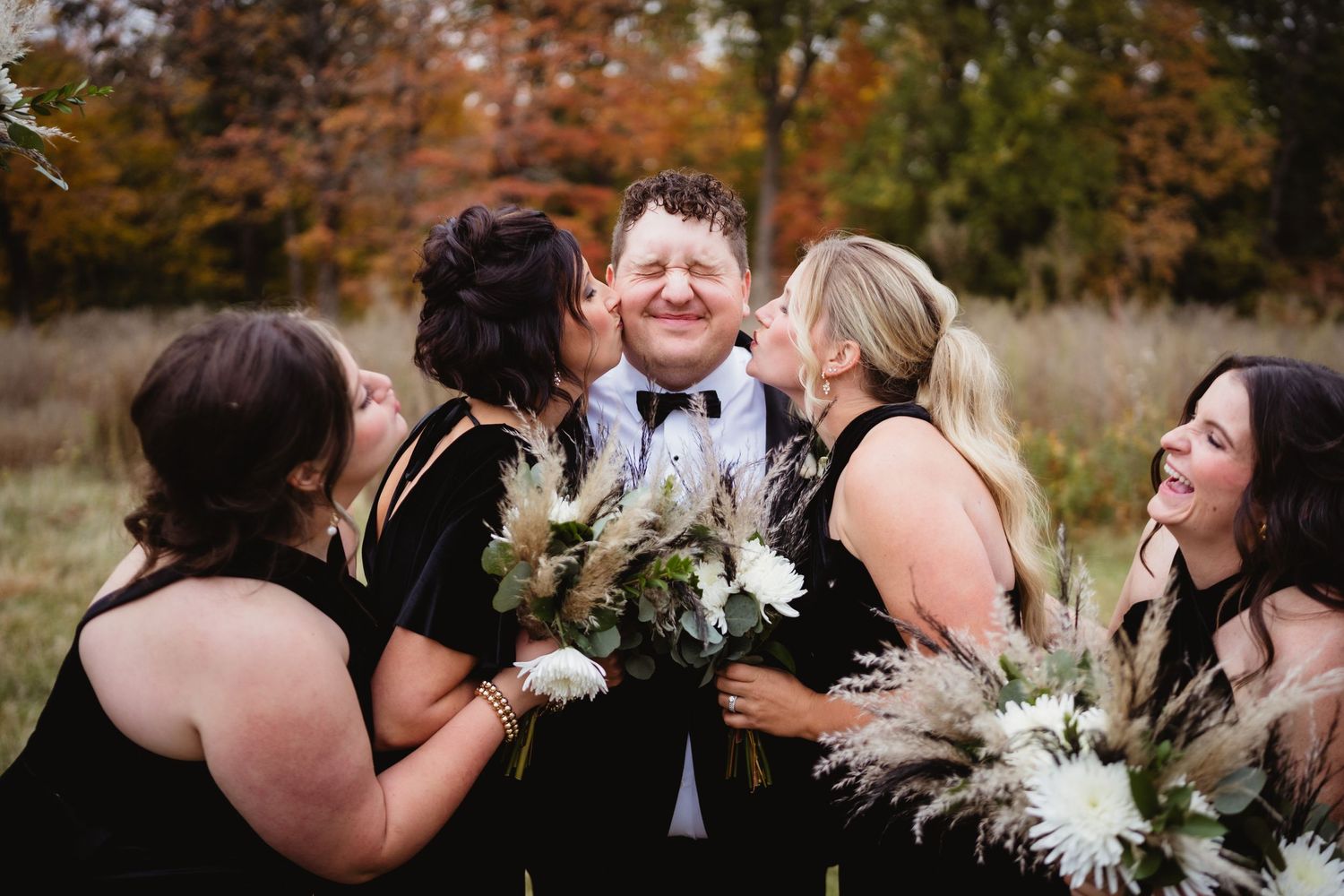 A group shares joyful moments and laughter during an outdoor autumn wedding celebration.