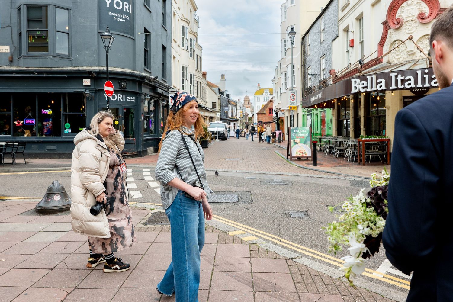 People walking and shopping on a busy urban street with storefronts and buildings on both sides.