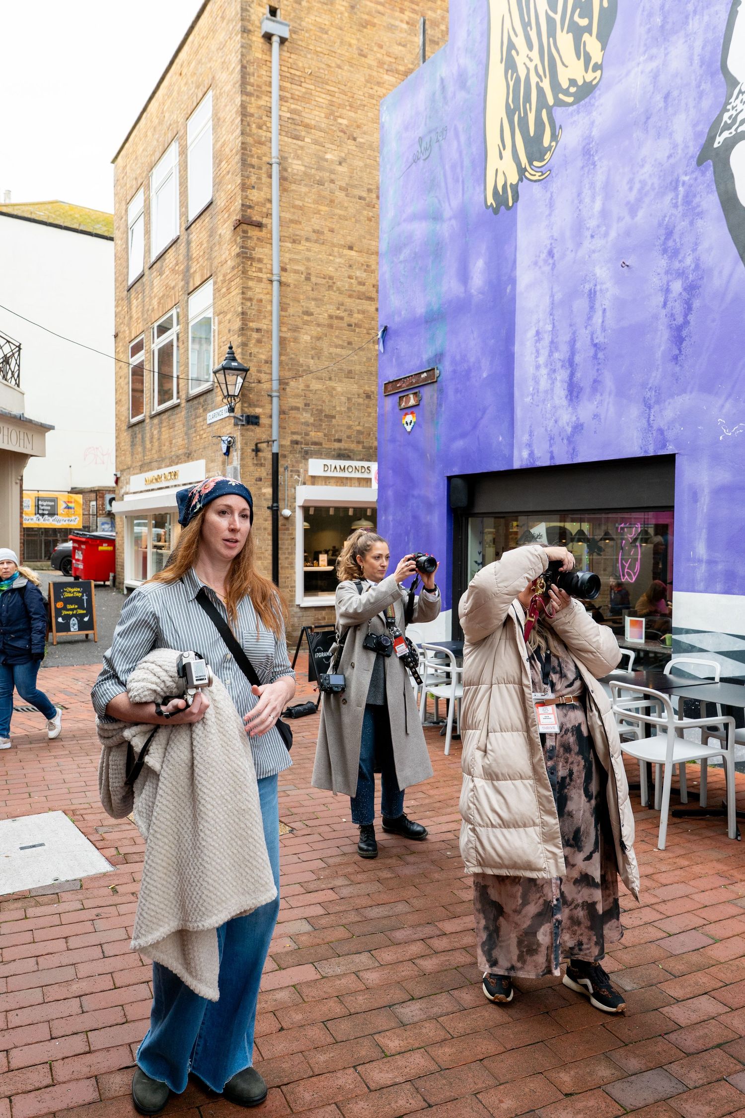 A sequence of five photos showing someone in a beige coat and blue jeans taking photos on a brick sidewalk.
