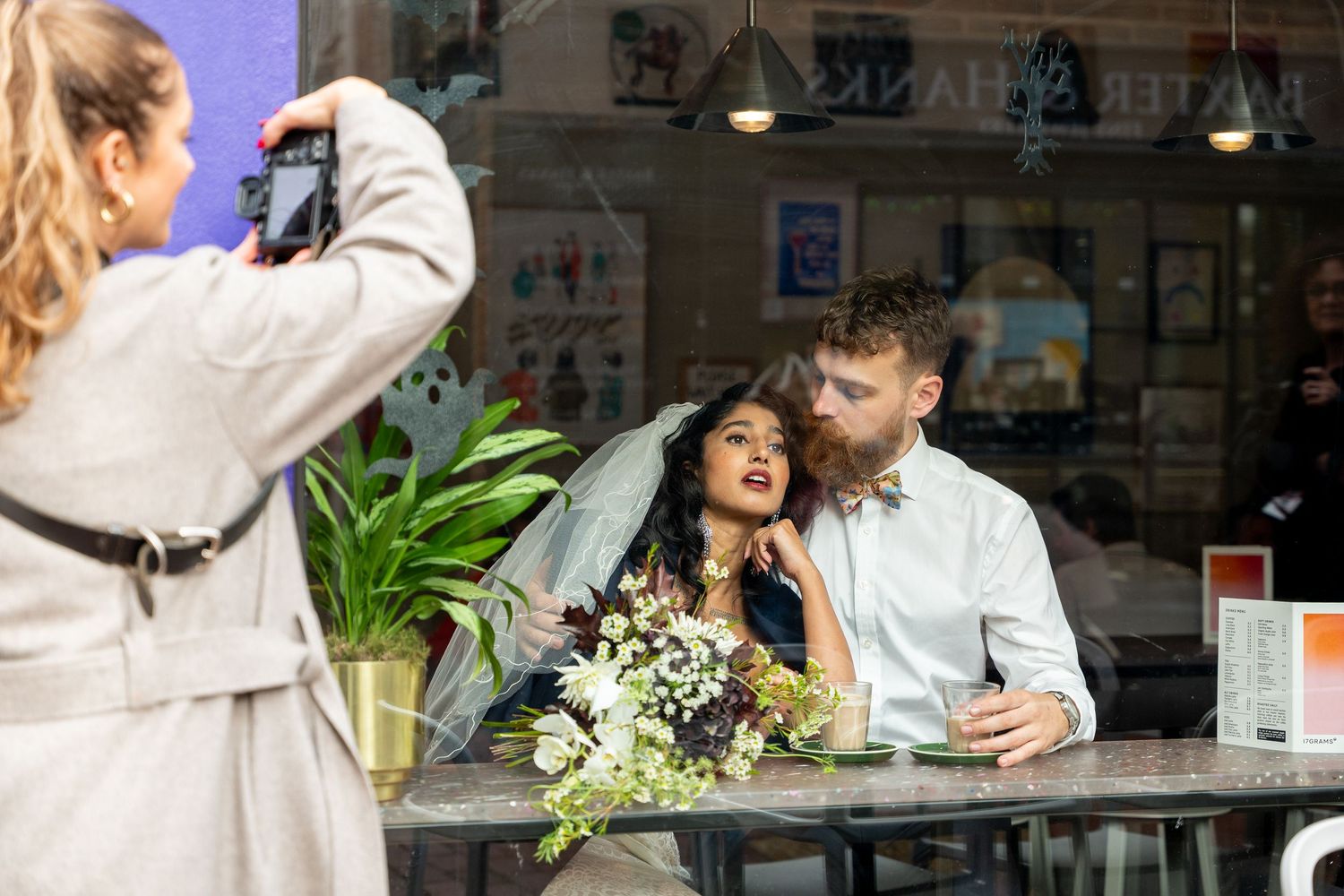 A couple shares a romantic moment at an outdoor cafe with white flowers on the table.