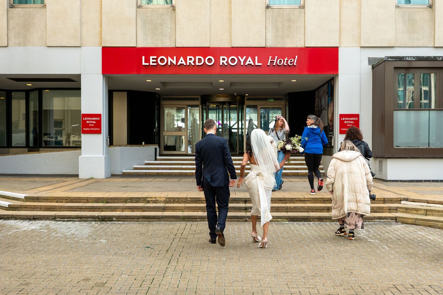 People walking towards the entrance of Leonardo Royal Hotel on a sunny day.