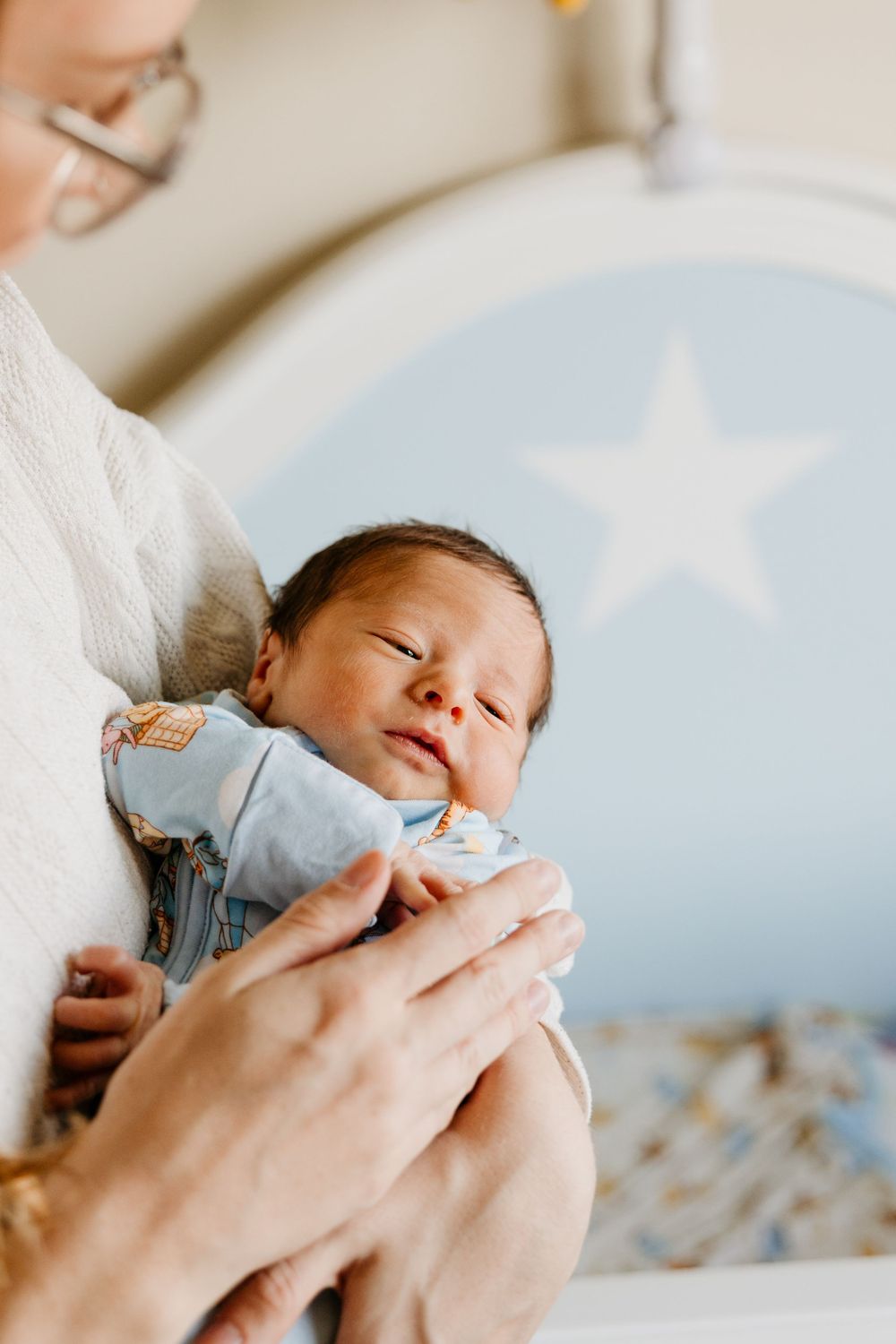 A series of tender close-up shots showing hands gently caring for a sleeping newborn baby.