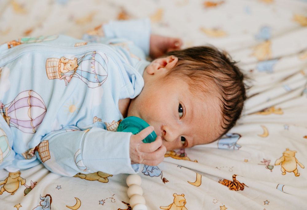 A sleeping child rests peacefully on white bedding with cartoon animal prints.