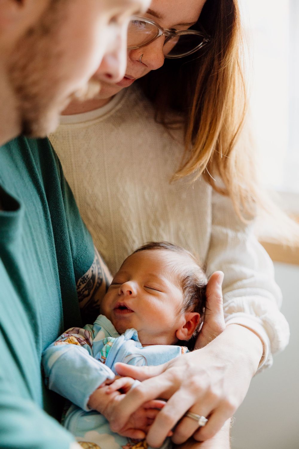 Tender moments of a newborn baby being cradled in soft lighting.