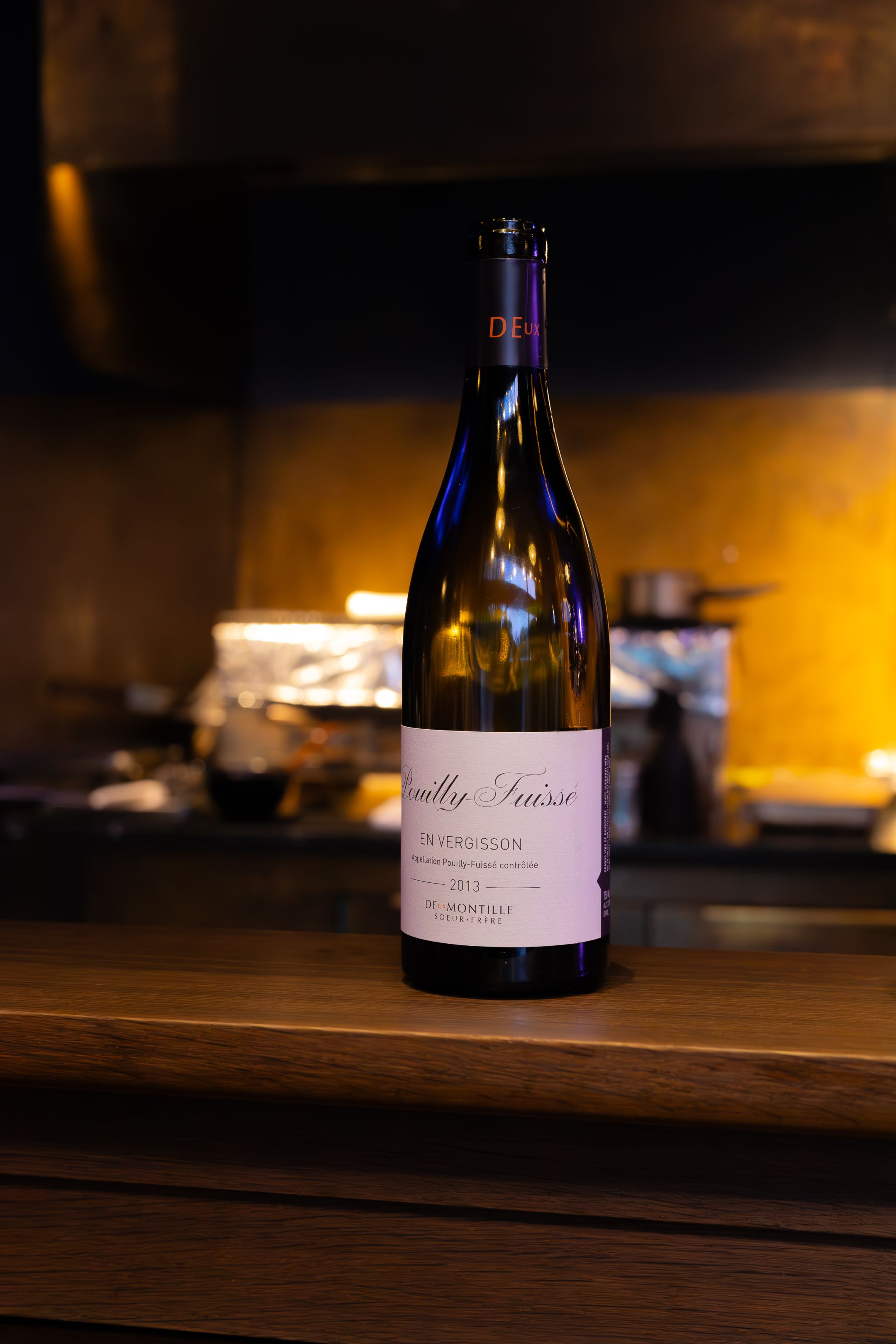 Wine bottle silhouetted against a dark background with warm ambient lighting creating a moody atmosphere.