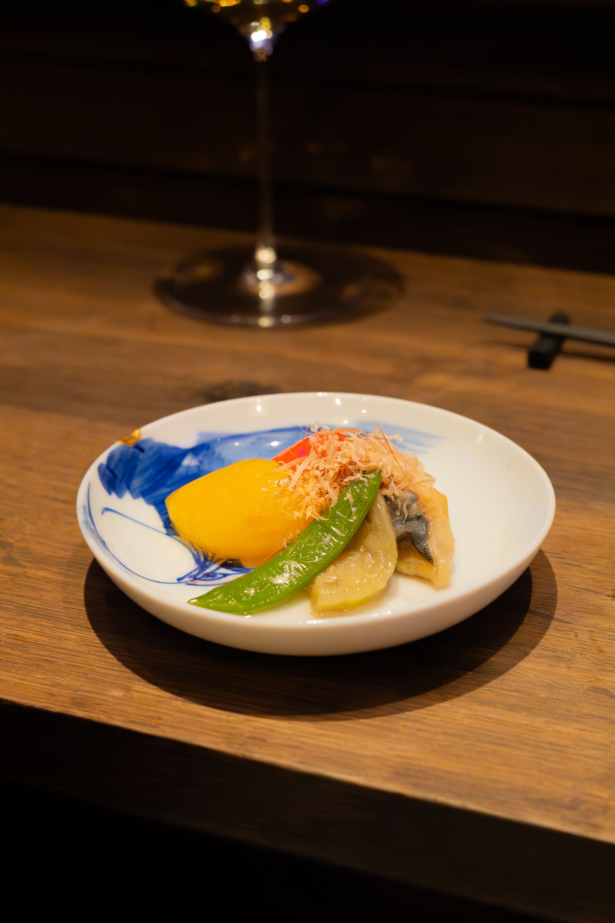 Artfully plated sushi dish with fresh fish and garnishes on a white ceramic plate against a dark wooden surface.
