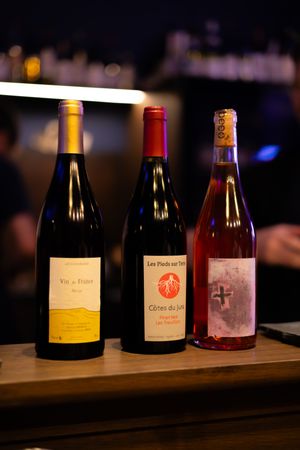 Row of wine bottles arranged on a wooden surface with varied labels and styles illuminated by soft lighting.