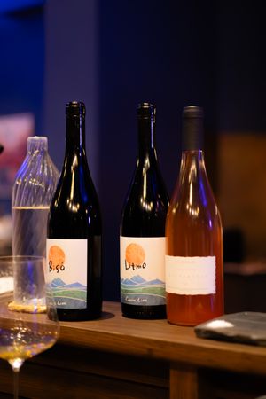 Row of wine bottles and glasses arranged on a dark table with ambient lighting.