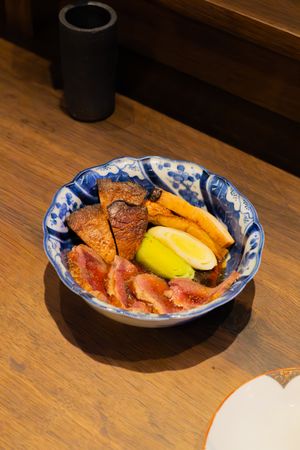 Plates of sashimi and seafood served on traditional blue and white patterned dishes on a wooden table.