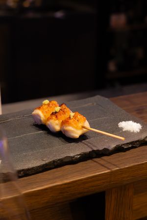 Close-up of sushi pieces served on dark stone plates with garnish and salt.