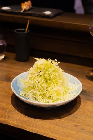 A large portion of finely shredded fresh cabbage served on a white plate atop a wooden surface.