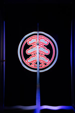 A neon sign displaying a stylized brain-like design in red and blue colors against a black background.