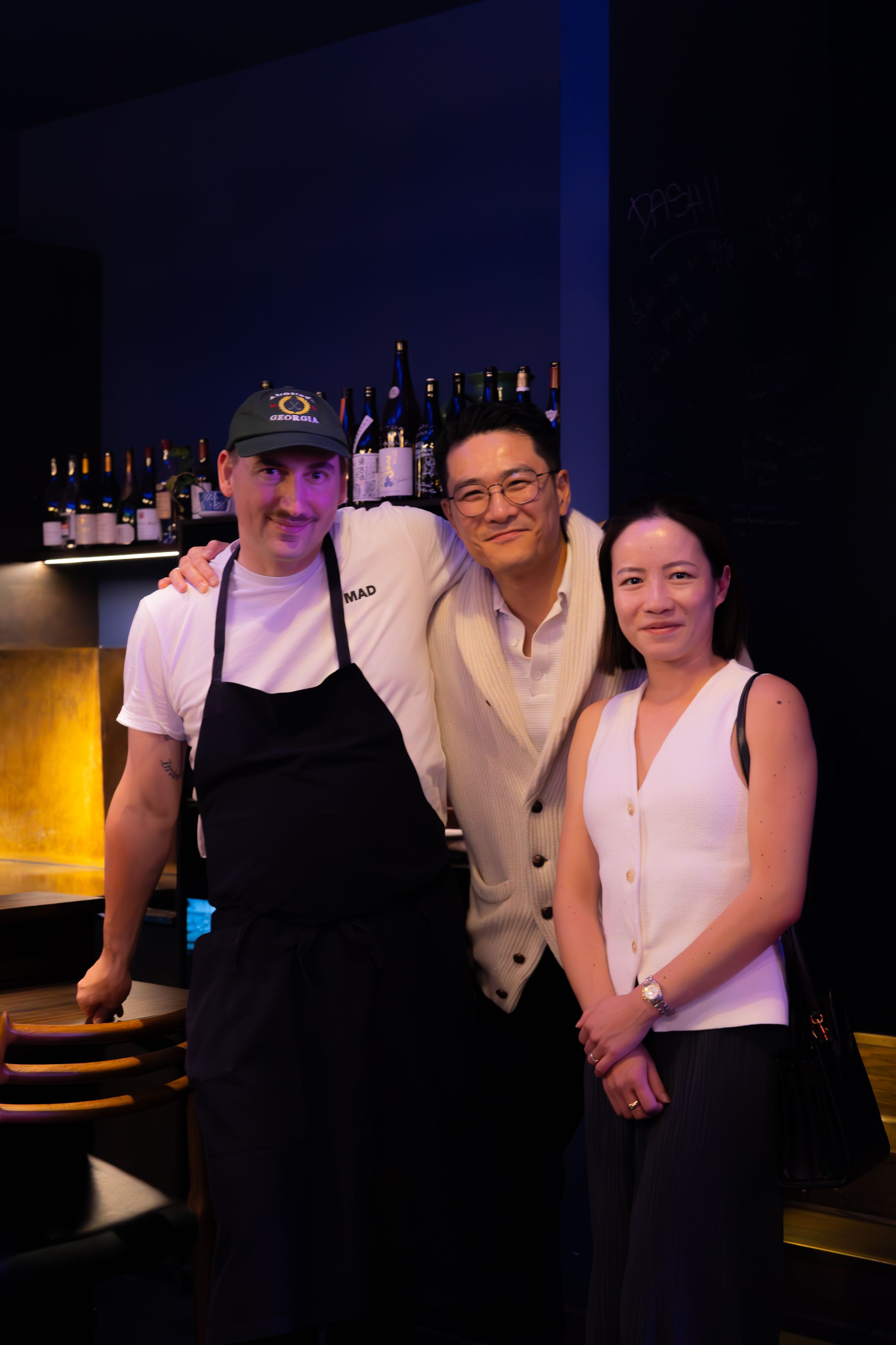 Restaurant staff posing together in formal attire at a dimly lit dining establishment.