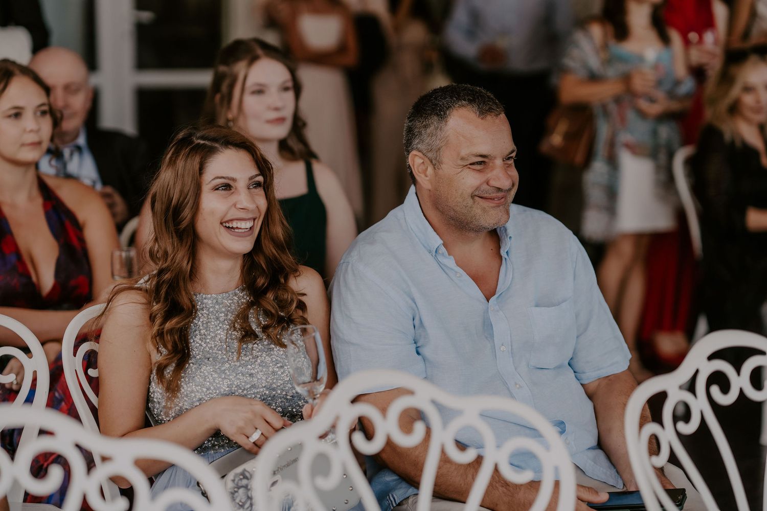 Guests at a wedding reception smile and celebrate together in a festive indoor setting.