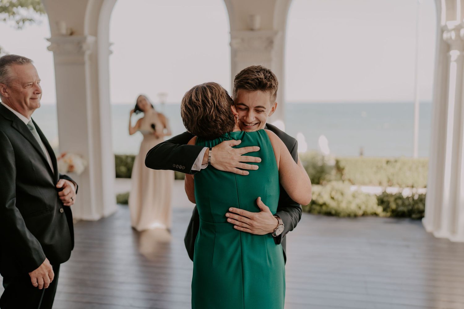 Emotional embraces shared between guests on an elegant white columned porch.