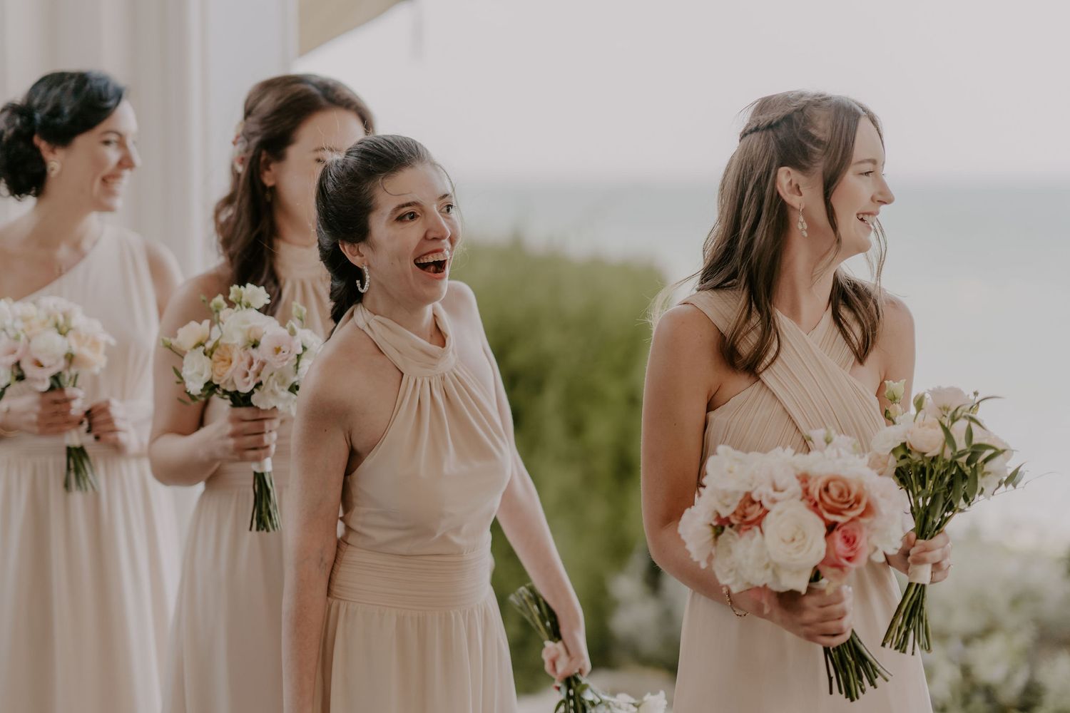 Wedding party members share candid moments of joy and laughter outdoors.