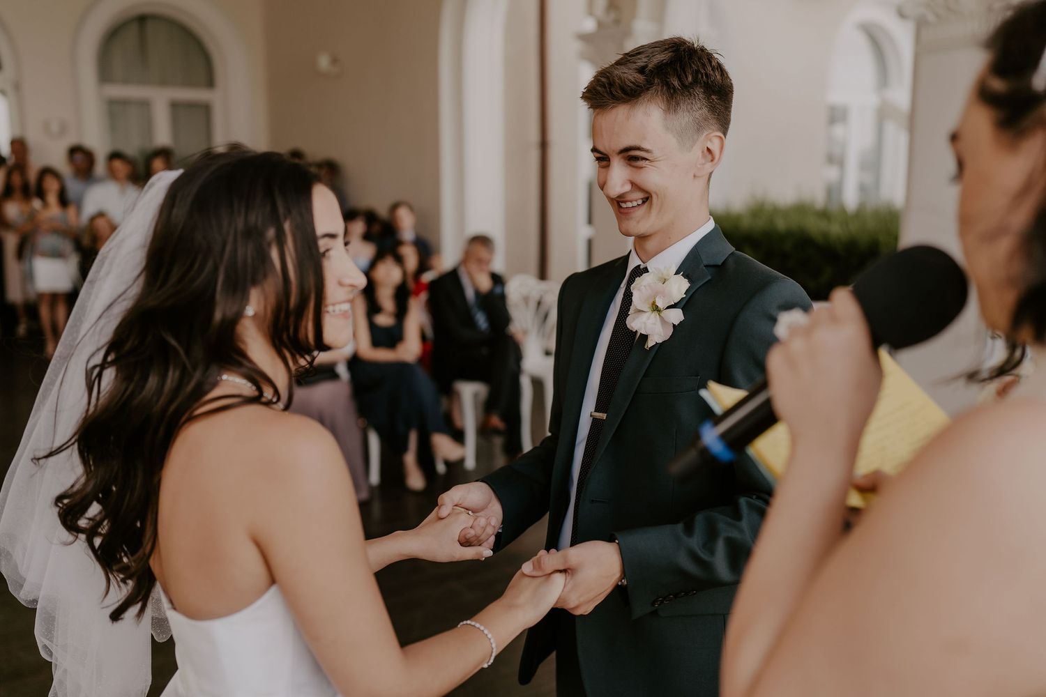 Candid moment during wedding ceremony showing couple exchanging rings under white arches.