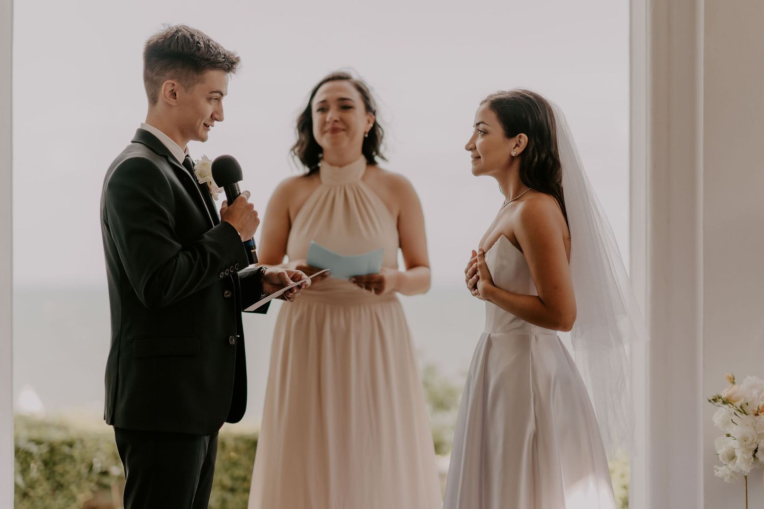 Intimate wedding ceremony moment captured under white archway with natural lighting.