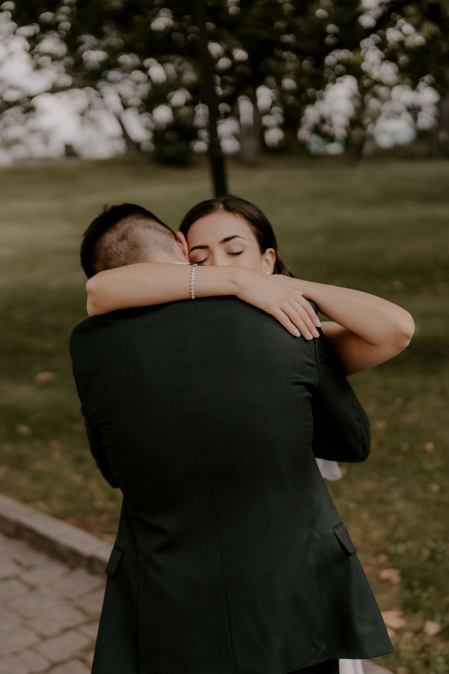 A tender embrace between newlyweds in a sunlit garden setting.