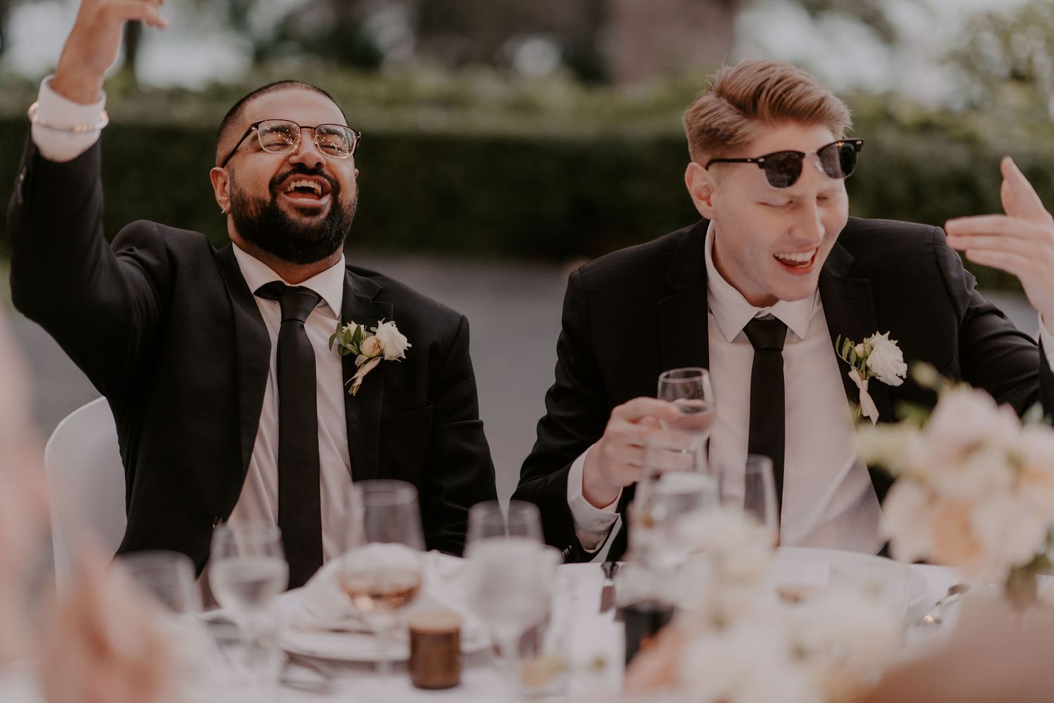 Wedding reception guests laughing and celebrating at decorated outdoor tables.