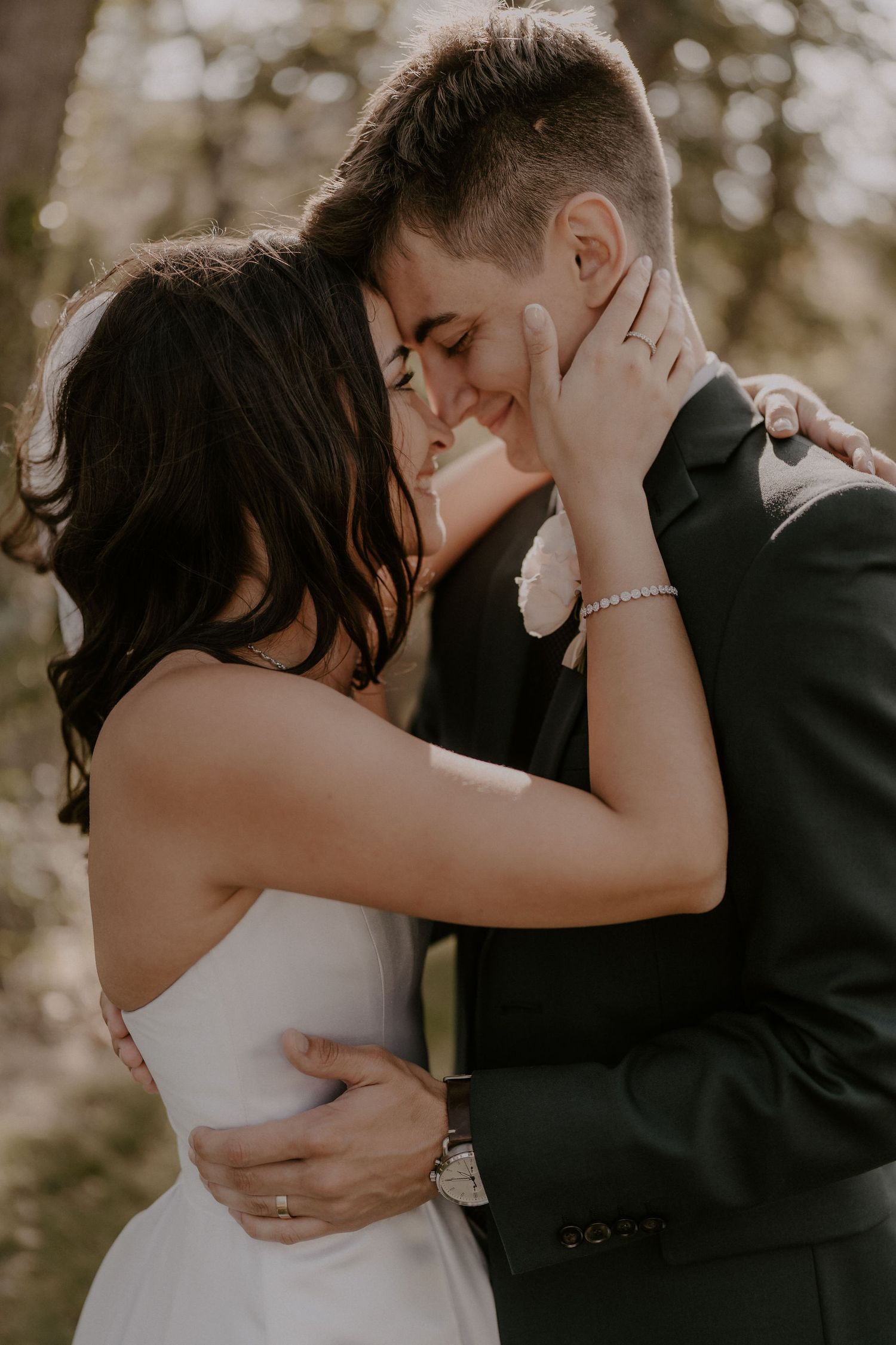 An intimate moment between newlyweds sharing a tender embrace in warm sunlight.