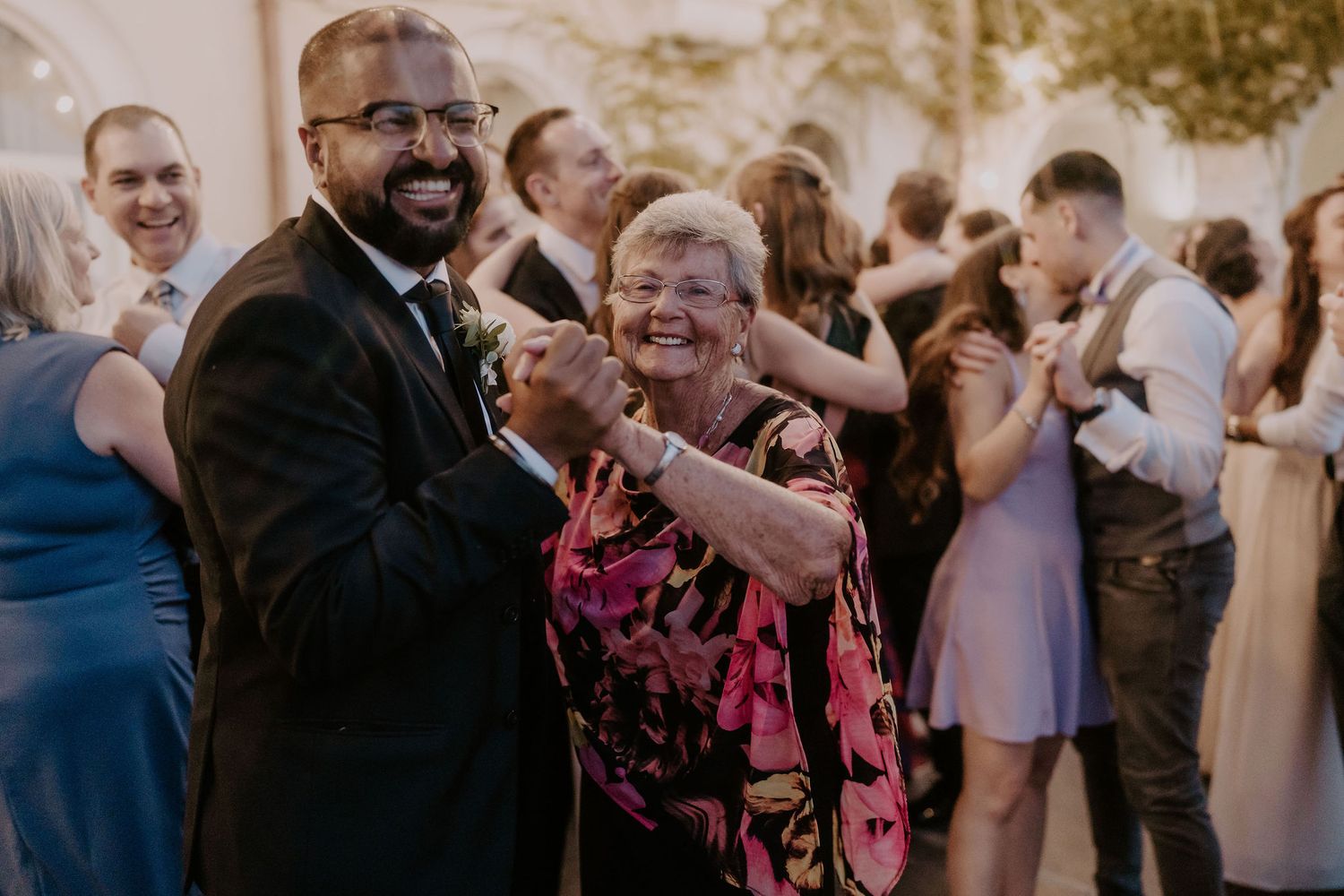 Guests share laughs while dancing together at an elegant indoor wedding reception.