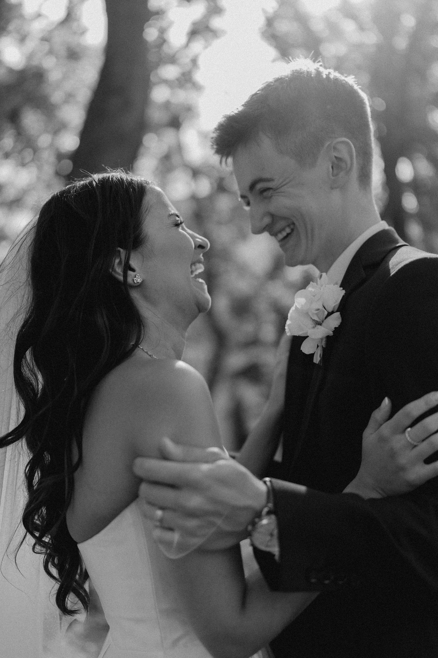 A candid moment of pure joy between newlyweds laughing together outdoors.
