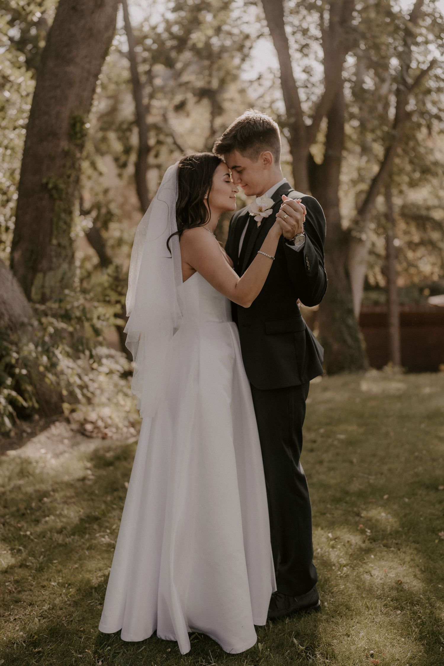 A romantic dance between newlyweds in a sunlit garden setting.