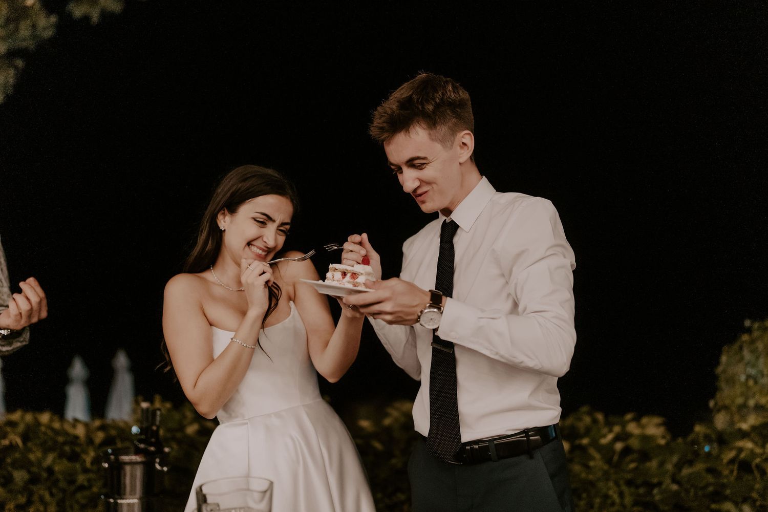 A couple feeds each other wedding cake during their reception celebration.