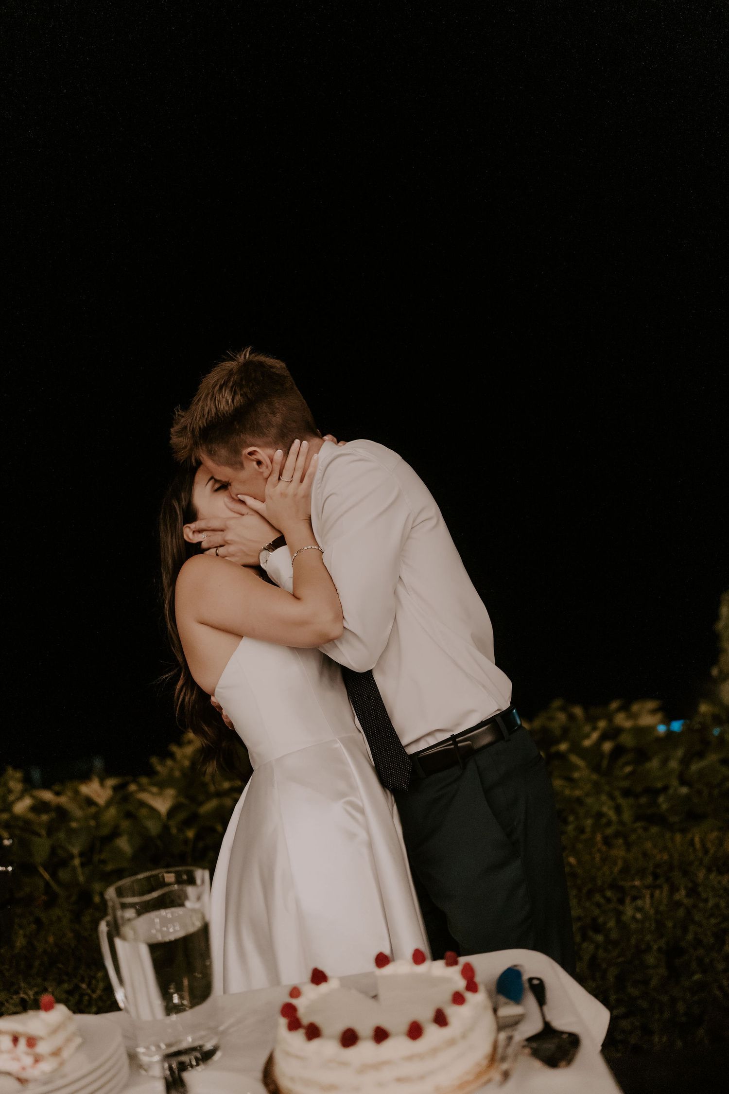 Bride and groom share a playful moment while cutting their wedding cake.