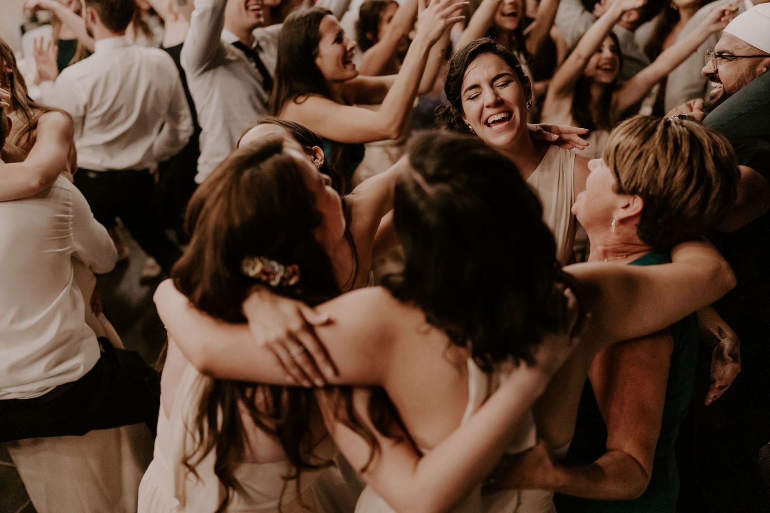 Guests dance and celebrate at a dimly lit wedding reception party.