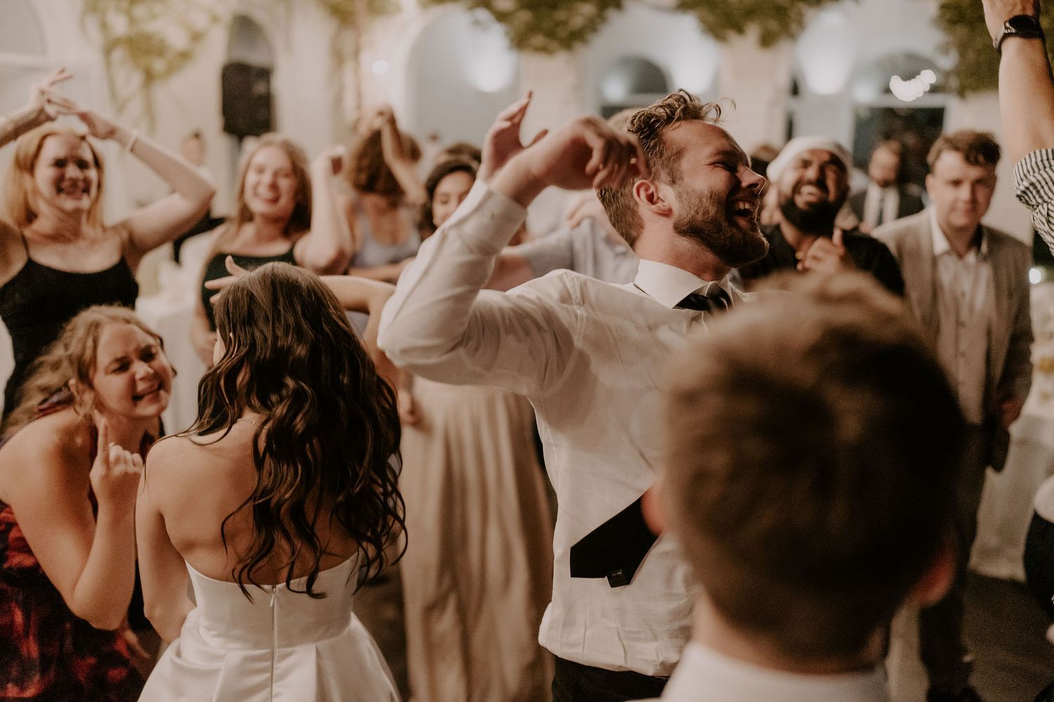 Wedding reception guests dancing and celebrating joyfully on the dance floor.
