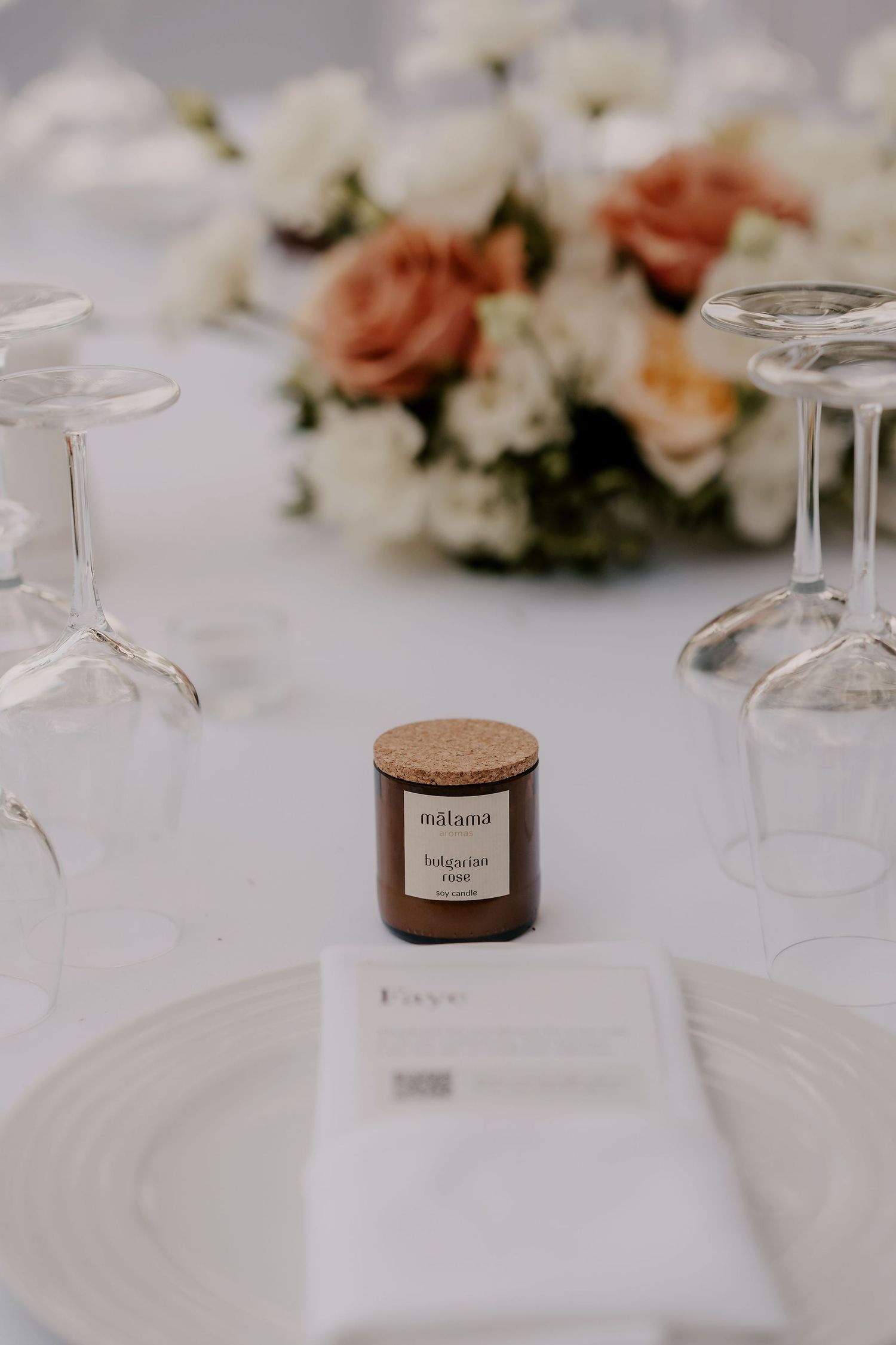 Elegant table setting with wooden place card holders and upturned wine glasses on white linens.