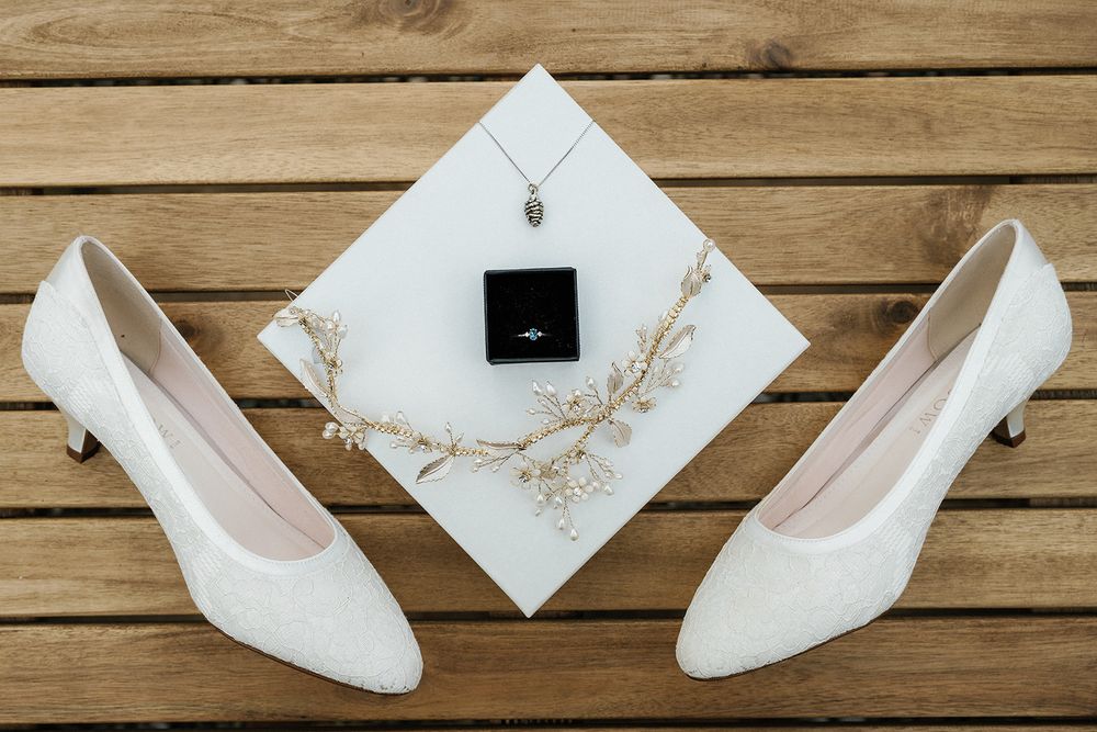 White bridal shoes arranged artistically on wooden planks with decorative elements.