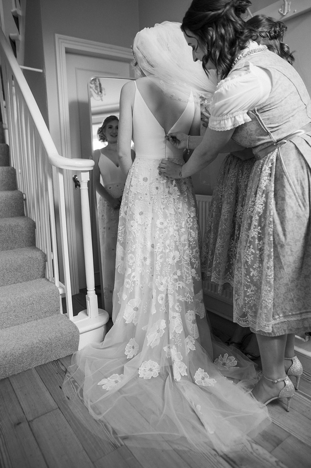 Black and white photo of wedding dress preparations on a staircase with traditional dirndl details.