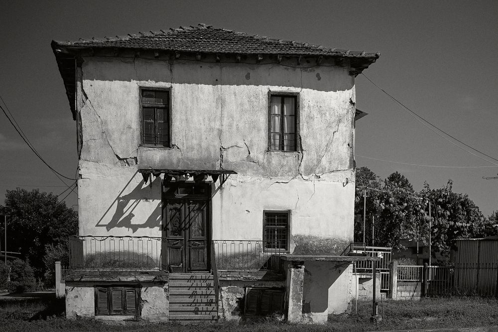 A series of six black and white photographs showing dilapidated buildings and rustic architecture in a rural setting.