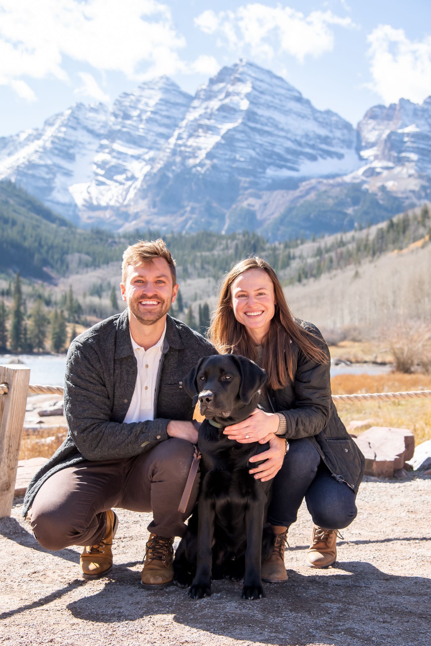 A cute couple and their dog in front of The Maroon Bells in Aspen Colorado after a surprise proposal