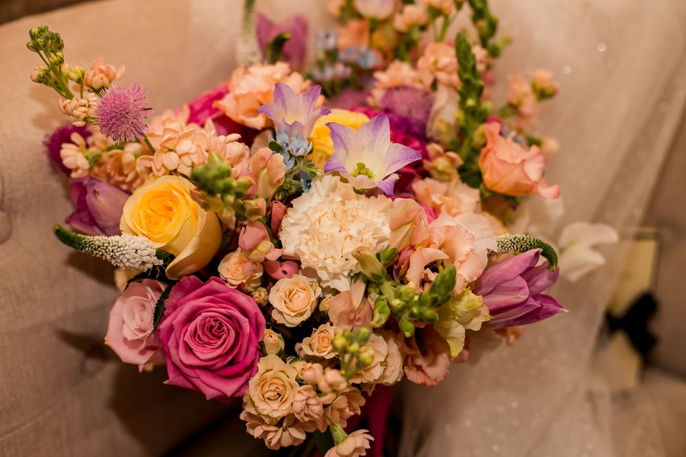 Vibrant wedding bouquets featuring pink roses, orange blooms and greenery arranged in a row.