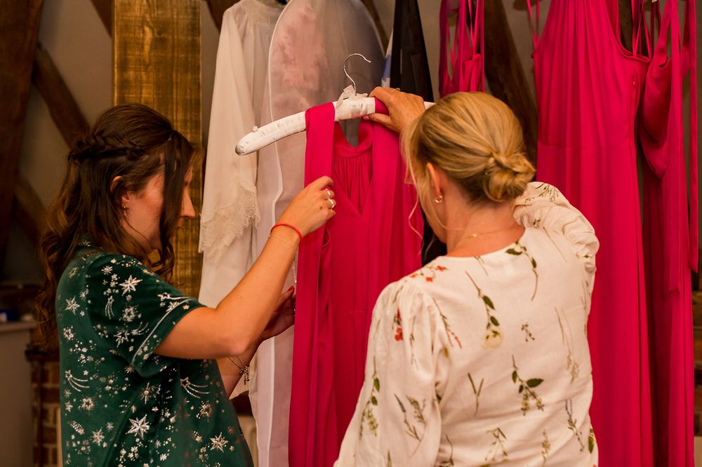 Friends gathered in a room with red dresses hanging in the background.