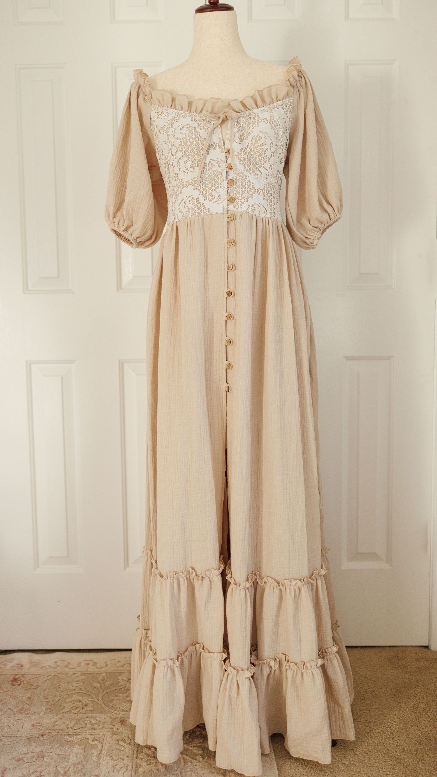 Rustic brown linen baby romper with delicate white lace trim and crochet details displayed on vintage lace background.