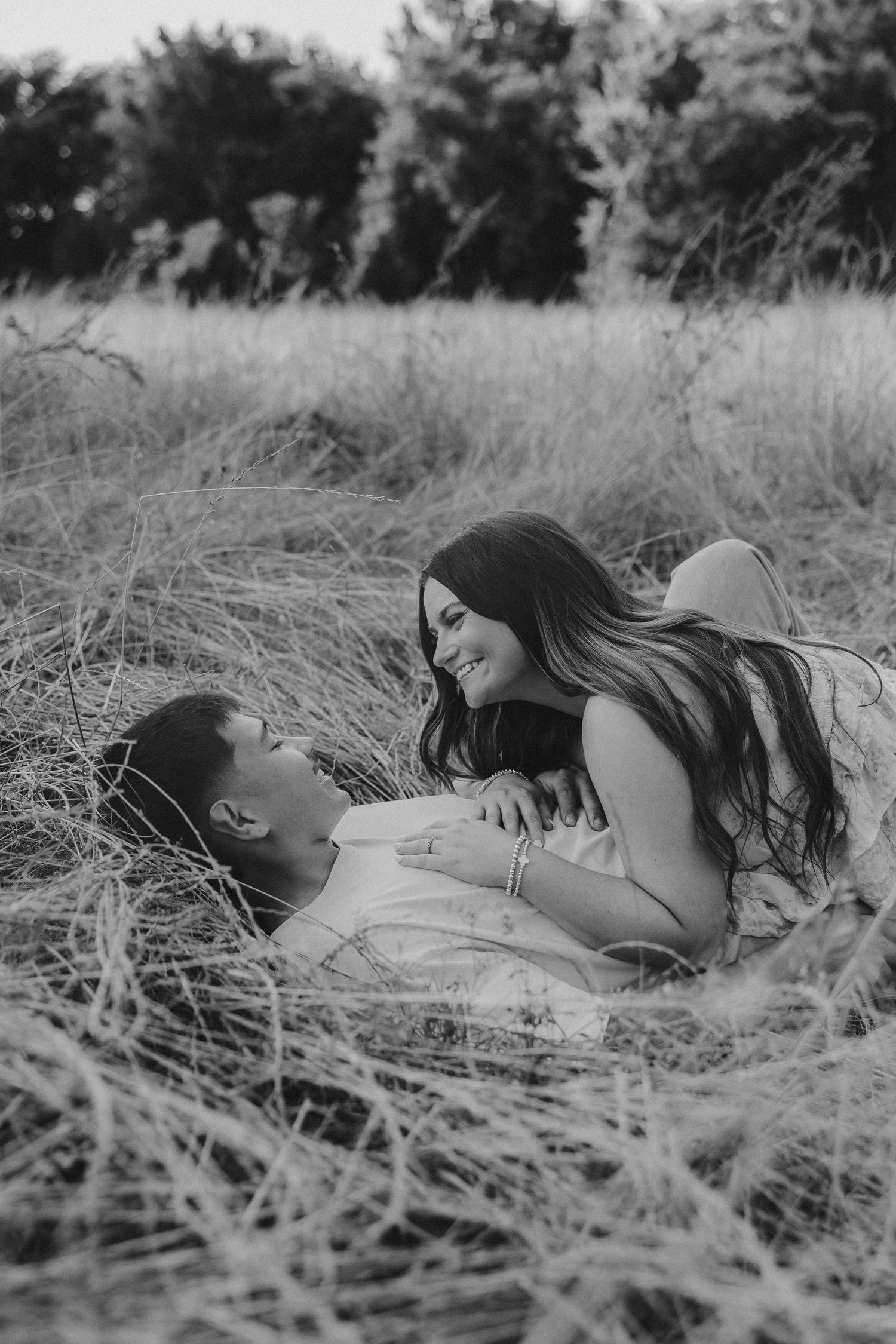 Loving couple embraces in golden sunset light in rustic field setting.